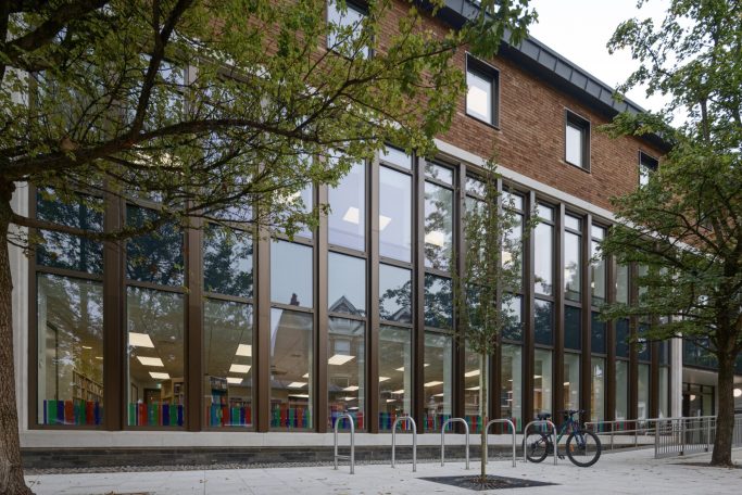 Weybridge Library Modern building with large windows, trees, and bicycle outside.